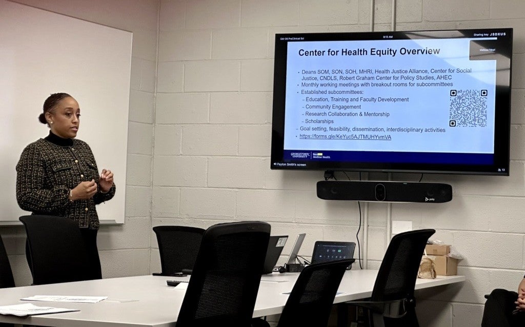 Chair of the Center for Health Equity, Dr. Michelle Roett, stands in front of a screen that reads, Center for Health Equity Overview